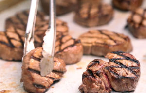 Chad Ryan | The Journal Gazette Sycamore Hills Executive Chef Nate Hiegel places grilled filet mignon steaks on a tray as he prepares for an event at Sycamore on Monday. Hiegel will be part of a team of chefs, including a celebrity chef, who will collaborate for the annual Blessings in a Backpack fundraiser.