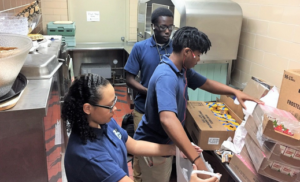 Bishop Grimes High School seniors Katie Collins, left, Marlyn Brown, center, and Lual Lual, rear, pack bags of food for students at Franklin Elementary School in Syracuse.(James T. Mulder) 